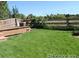 Well-maintained backyard with lush green grass, a wooden fence, and a small deck at 7982 S Kittredge Way, Englewood, CO 80112