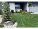 Beautifully landscaped front yard with lush green grass, decorative rocks, flowering plants, and a modern home facade at 6610 Barnstead Dr, Castle Pines, CO 80108