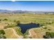 An aerial view captures a scenic park featuring a lake, walking paths, and mountain views in the distance at 3308 W 11Th Avenue Pl, Broomfield, CO 80020