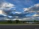 A wide shot of scenic park under a bright sky with fluffy clouds, features a pond, trees, and walking paths at 3308 W 11Th Avenue Pl, Broomfield, CO 80020