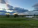 A serene pond is nestled in a lush green field, set against a backdrop of a cloudy sky at sunset at 3308 W 11Th Avenue Pl, Broomfield, CO 80020