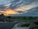The house looks across the street towards an open field with mountains under a colorful sunset sky at 3308 W 11Th Avenue Pl, Broomfield, CO 80020
