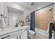 Clean bathroom featuring a modern vanity, neutral tile floors, shower with blue curtain, and good lighting at 17164 W 91St Ln, Arvada, CO 80007
