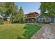 Backyard view features a deck, patio, blue siding, well kept lawn, and mature trees with plenty of shade at 9325 Utica St, Westminster, CO 80031