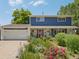 Charming two-story home with a blue exterior, beautiful landscaping and a red front door at 9325 Utica St, Westminster, CO 80031