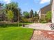 Landscaped backyard featuring a grassy lawn, mature trees, and a concrete patio at 11842 Altura St, Commerce City, CO 80603