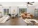 Bright living room boasts hardwood floors, a ceiling fan, and a modern leather couch at 11842 Altura St, Commerce City, CO 80603