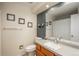 Bathroom vanity has a white sink and wood cabinets with a large mirror and decorative artwork at 11805 W 74Th Ave, Arvada, CO 80005