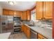 Spacious kitchen features stainless appliances, stone countertops and wood cabinets with wood-look flooring at 11805 W 74Th Ave, Arvada, CO 80005