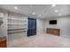 Finished basement area featuring carpeting, storage shelves, dark curtains, and a television at 9407 W Gibraltar Pl, Littleton, CO 80127
