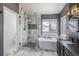 Modern bathroom featuring a soaking tub, glass-enclosed shower, dual vanities, and stylish lighting fixtures at 9407 W Gibraltar Pl, Littleton, CO 80127