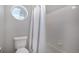 Bathroom featuring a toilet, white tile surround in the shower, and a round accent window at 9407 W Gibraltar Pl, Littleton, CO 80127