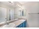 Functional bathroom featuring dual sinks, blue cabinetry, a large mirror, and good lighting at 9407 W Gibraltar Pl, Littleton, CO 80127
