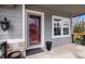 Inviting covered porch with a stylish red door, neutral siding, and classic exterior lighting fixture at 9407 W Gibraltar Pl, Littleton, CO 80127