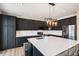 Modern kitchen features a large island with quartz countertops, dark cabinetry, and stainless steel appliances at 9407 W Gibraltar Pl, Littleton, CO 80127