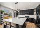Well-lit kitchen features a large island with seating, black cabinetry, stainless steel appliances, and wood floors at 9407 W Gibraltar Pl, Littleton, CO 80127
