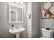 Elegant powder room featuring a pedestal sink, toilet, and decorative artwork on the wall at 9407 W Gibraltar Pl, Littleton, CO 80127
