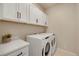 Convenient laundry room featuring a white washer and dryer set, white cabinets, countertop, and dark hardware at 1933 W 165Th Way, Broomfield, CO 80023