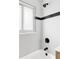 White tiled shower and tub combination with black accent stripe and fixtures at 2340 Jamaica St, Aurora, CO 80010