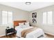 Bright bedroom with two windows, light walls, hardwood floor, brown headboard, and accent wall art at 2340 Jamaica St, Aurora, CO 80010