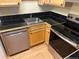 Bright kitchen featuring stainless steel appliances, wood cabinets, and black tile countertops at 5995 W Hampden Ave # 3E, Denver, CO 80227