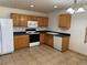 Functional kitchen with wooden cabinets, standard appliances, and tile flooring, perfect for culinary endeavors at 897 Mockingbird Ln, Brighton, CO 80601