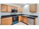 An efficient kitchen features tile flooring, oak cabinets, black countertops, and appliances at 897 Mockingbird Ln, Brighton, CO 80601