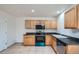 An efficient kitchen features tile flooring, oak cabinets, black countertops, and appliances at 897 Mockingbird Ln, Brighton, CO 80601
