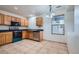An efficient kitchen features tile flooring, oak cabinets, black countertops, and appliances at 897 Mockingbird Ln, Brighton, CO 80601
