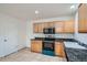 An efficient kitchen features tile flooring, oak cabinets, black countertops, and appliances at 897 Mockingbird Ln, Brighton, CO 80601