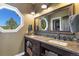 Well-lit bathroom featuring a double vanity, granite countertops, and storage shelves at 17015 Oxbridge Rd, Monument, CO 80132