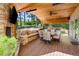 Comfortable covered patio featuring a stone fireplace, outdoor kitchen, and beautiful views of the surrounding trees at 17015 Oxbridge Rd, Monument, CO 80132
