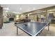 Open-concept game room with ping pong table, stone fireplace, and bar area at 17015 Oxbridge Rd, Monument, CO 80132