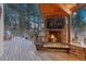 Relaxing outdoor deck featuring a stone fireplace, wood flooring, and scenic wooded views at 17015 Oxbridge Rd, Monument, CO 80132
