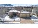 Tan two-story house with attached two-car garage, snowy yard, and mountain views at 17364 W 63Rd Dr, Arvada, CO 80403