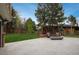 An expansive backyard with stone patio, green lawn, a steel pergola with seating, and a modern fire pit at 5164 E Princeton Ave, Cherry Hills Village, CO 80113