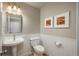 A cozy half bathroom features a pedestal sink, toilet, and decorative wall art, complemented by wainscoting at 5164 E Princeton Ave, Cherry Hills Village, CO 80113