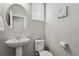 Cozy half-bathroom with a pedestal sink, a round mirror, and a white toilet, enhanced by natural light at 4770 N Jasper St, Denver, CO 80239