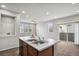 Open concept kitchen with a white countertop island with stainless sink and view to an open, window-lit living room at 4770 N Jasper St, Denver, CO 80239