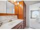 Cozy bathroom featuring a wood cabinet, mirror, sink, and doorway leading into a bedroom at 7801 W 35Th Ave # 405, Wheat Ridge, CO 80033