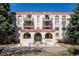 Facade of condo building featuring brickwork, balconies, a central entrance, and meticulous landscaping for a welcoming appeal at 7801 W 35Th Ave # 405, Wheat Ridge, CO 80033