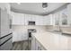A modern kitchen featuring white cabinets, stainless steel appliances, a large island, and gray plank flooring at 26890 E Roxbury Pl, Aurora, CO 80016