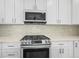 Close up of a stylish kitchen featuring stainless steel oven, white cabinets, and quartz countertops at 26890 E Roxbury Pl, Aurora, CO 80016