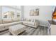 Bright, open living room with large windows, gray plank flooring, a comfortable sectional sofa and neutral decor at 26890 E Roxbury Pl, Aurora, CO 80016