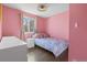 Light-filled bedroom with pink walls, hardwood floors, and a comfortable single bed at 17616 Ponderosa Ave, Parker, CO 80134