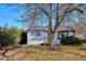 Charming home exterior with a green front door, small porch, and a mature tree in the yard at 1770 S Yuma St, Denver, CO 80223