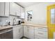 Bright kitchen featuring white cabinets, butcher block countertops, stainless steel dishwasher, and unique backsplash at 1770 S Yuma St, Denver, CO 80223