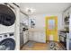 Bright kitchen with modern appliances, yellow door, white cabinets, and in-unit washer and dryer at 1770 S Yuma St, Denver, CO 80223