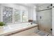 Bathroom features a soaking tub with tile surround, natural light from the window, and a glass shower at 920 Shady Oak Ln, Castle Pines, CO 80108