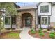 Close-up of the front entrance featuring a stone archway, gray siding, and manicured landscaping at 920 Shady Oak Ln, Castle Pines, CO 80108